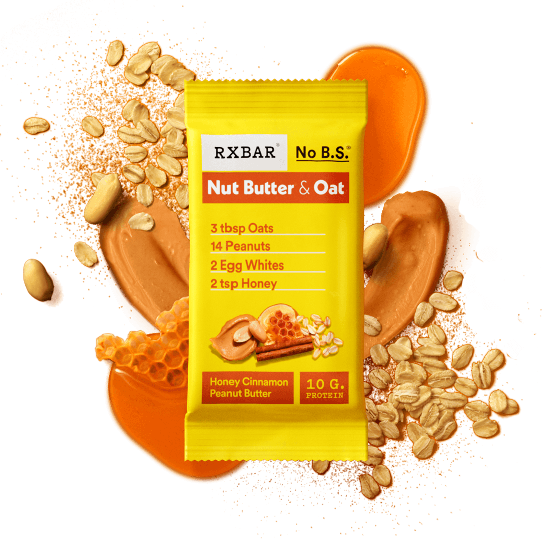 RXBAR nut butter and oat honey cinnamon peanut butter bar surrounded by honey, peanuts, peanut butter, and oats, on an orange background